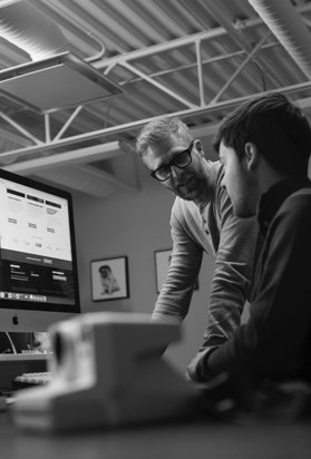 Two people discussing a website displayed on a computer screen